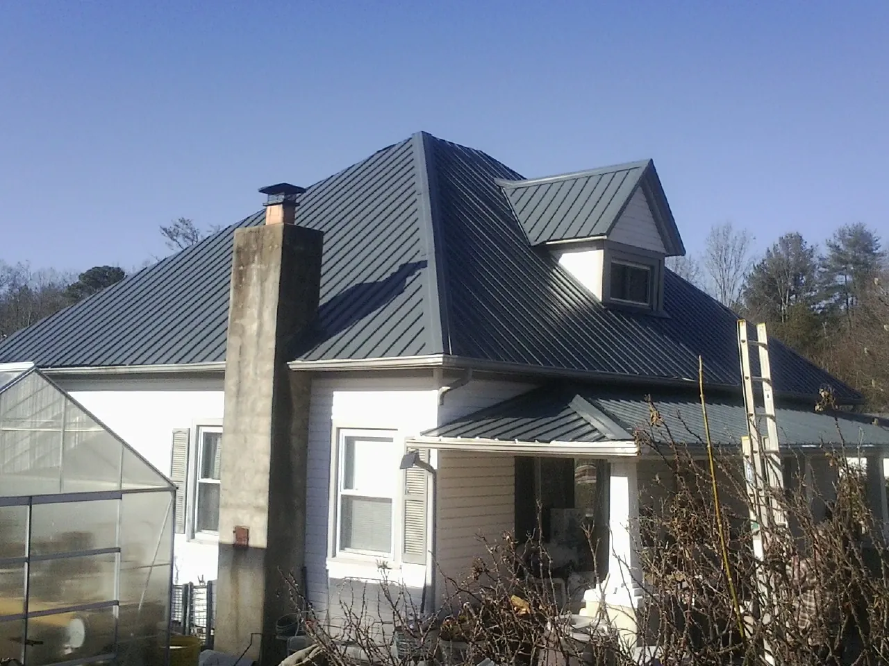 Dark blue standing seam metal roof on a white farmhouse with dormer — Slate & Tile Roof Repair by Roofing Brothers in North Little Rock