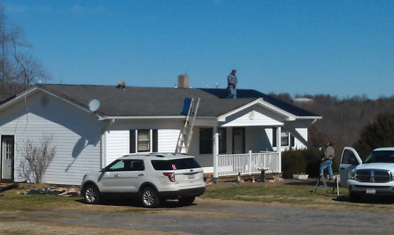Roofers stripping shingles from a white ranch house roof in North Little Rock