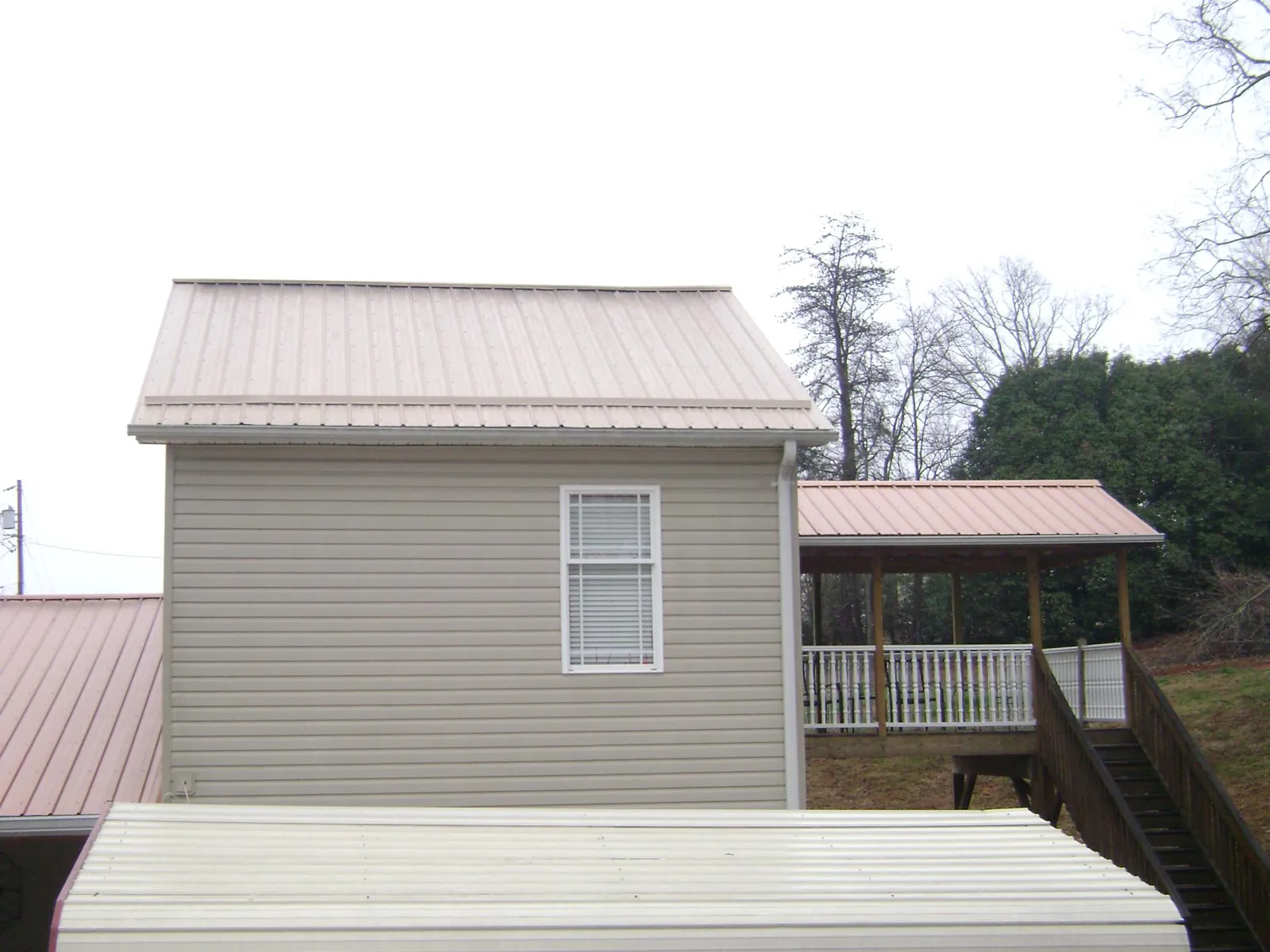 Tan metal roofs on a two story addition and attached porch, from a Roof Replacement job in North Little Rock
