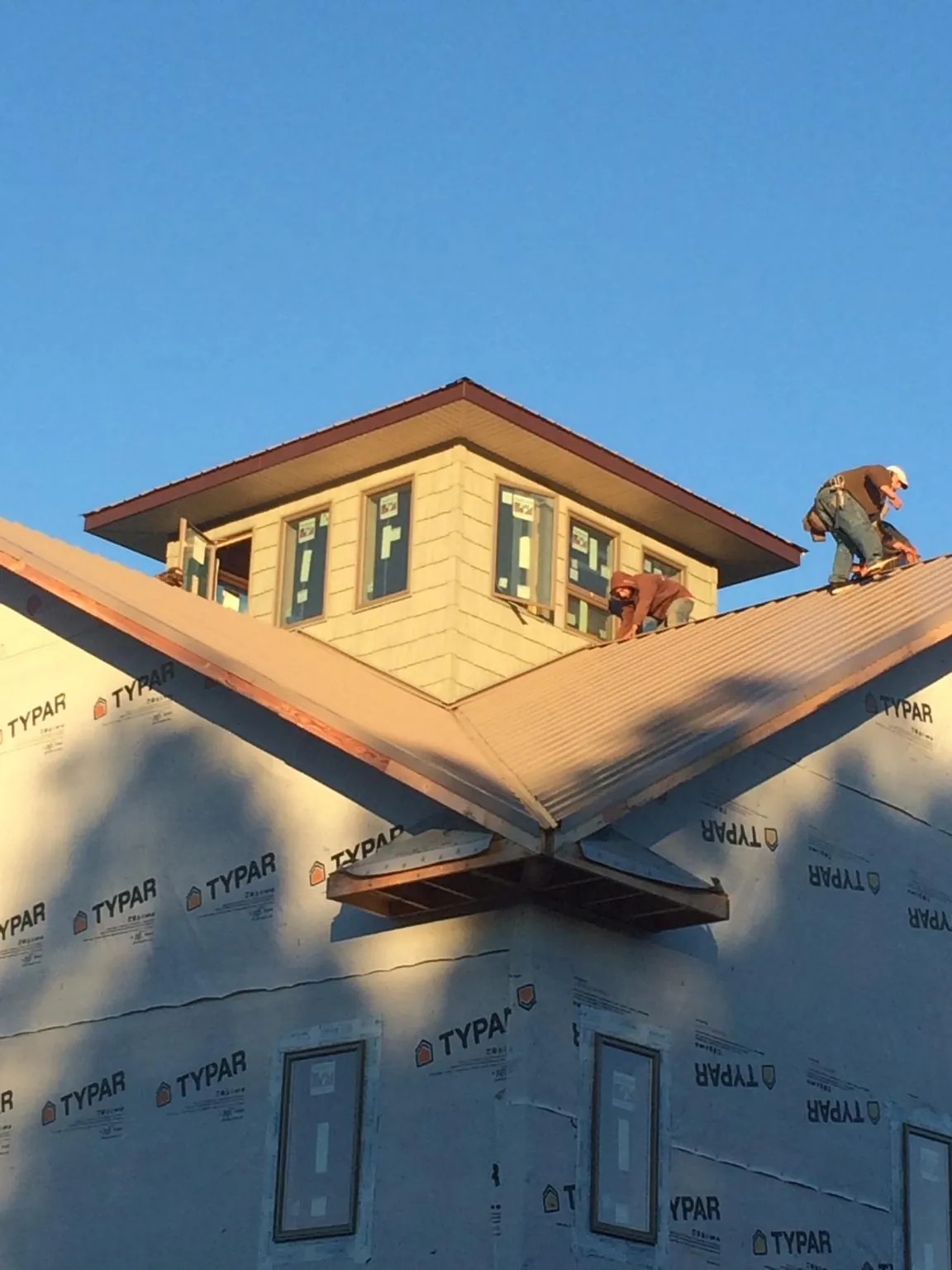 Roofers working around a rooftop cupola on a new metal roof at sunset — Roof Waterproofing in North Little Rock by Roofing Brothers